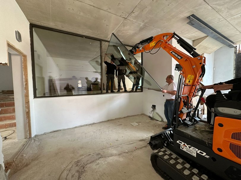 Miniexcavadora Develon DX20Z-7 colocando cristales en una vivienda unifamiliar